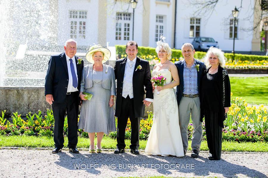 Hochzeits-Foto-Reportage Bad Tölz, Gruppenbild Brautpaar mit Eltern vor dem Springbrunnen