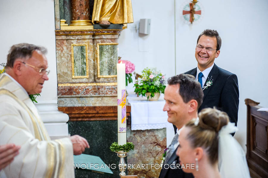 Hochzeit Fotograf Chiemsee, Brautpaar und lachender Trauzeuge bei der Trauung